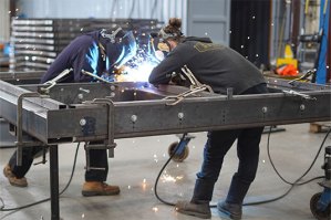 two PUI employees welding with sparks flying